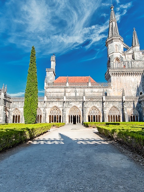 Abbey of Batalha Monastery with Gothic architecture and manicured gardens in Portugal.