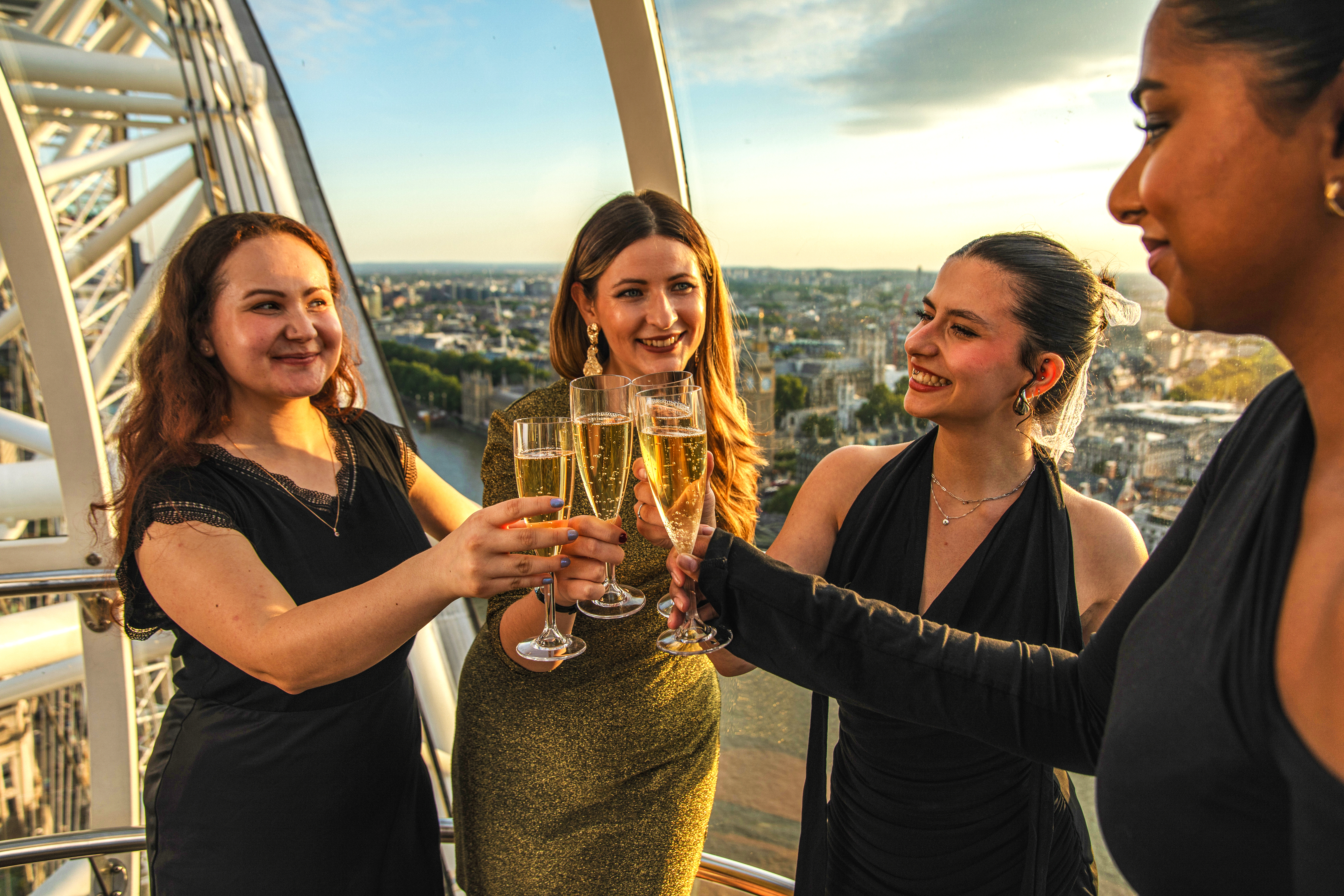Group toasting with champagne inside London Eye capsule during sunset.