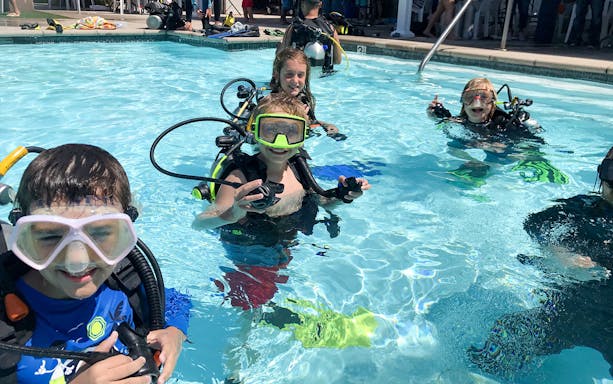 Children learning scuba diving in a pool at Palm Jumeirah, Dubai.