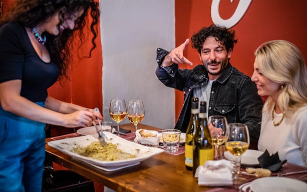 Guide serving pasta to guests on a food tour in Rome.
