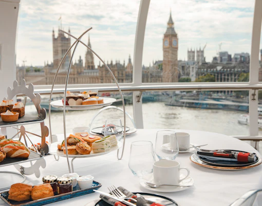 Afternoon tea setup inside the London Eye with views of Big Ben and the Thames.