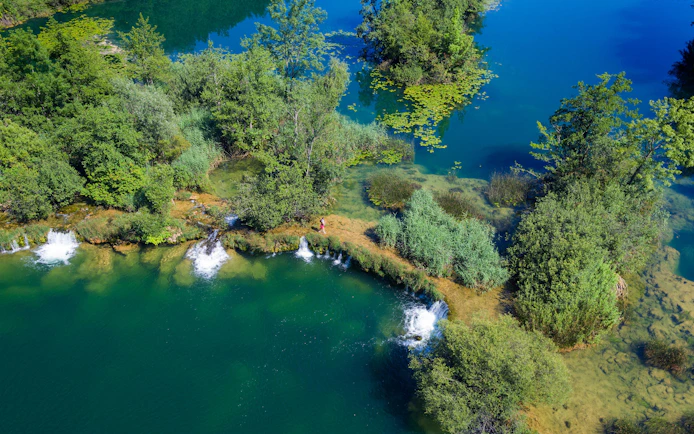 Aerial view of Mreznica River with small waterfalls and lush greenery, Croatia.