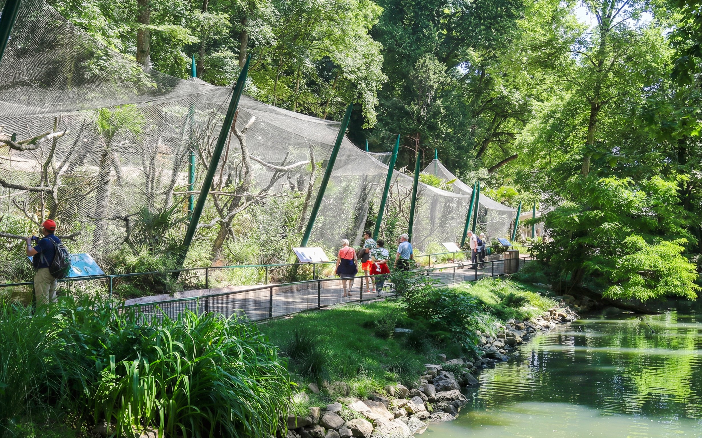 Visitors walking along a path beside animal enclosures at Zooparc de Beauval, Loire Valley, France.