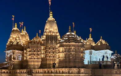 BAPS Hindu Temple illuminated at night, intricate carvings visible, Dubai tour.