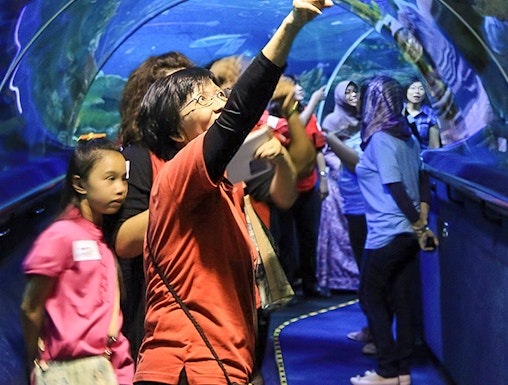 Visitors exploring the underwater tunnel at Aquaria KLCC, Kuala Lumpur.
