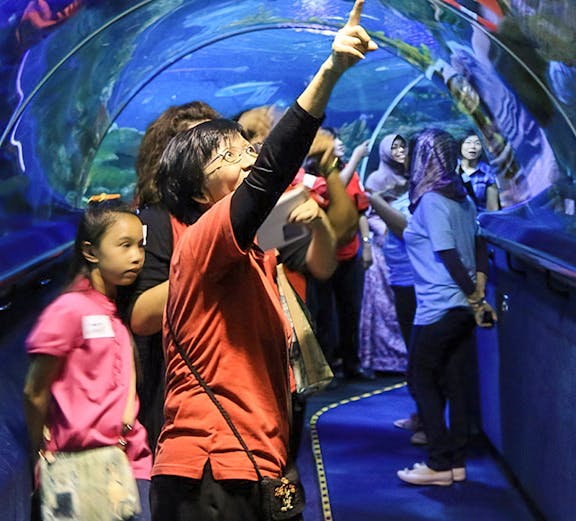 Visitors exploring the underwater tunnel at Aquaria KLCC, Kuala Lumpur.
