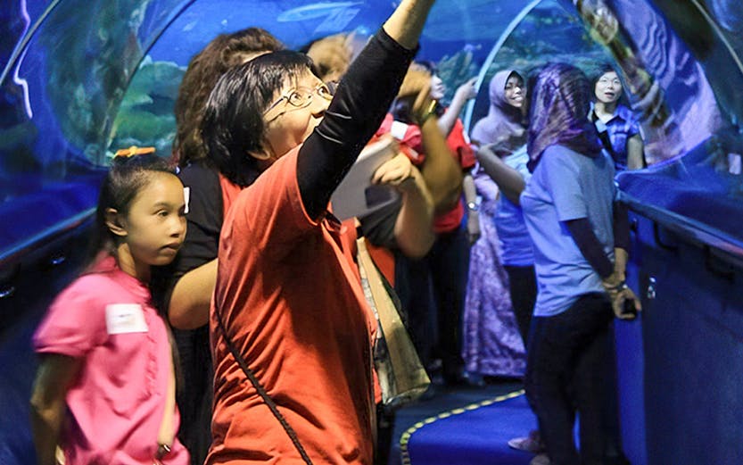 Visitors exploring the underwater tunnel at Aquaria KLCC, Kuala Lumpur.