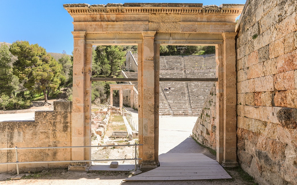 Epidaurus Ancient Theatre entrance with stone seating and surrounding greenery.