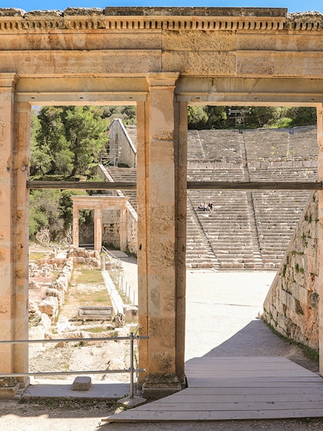 Epidaurus Ancient Theatre entrance with stone seating and surrounding greenery.