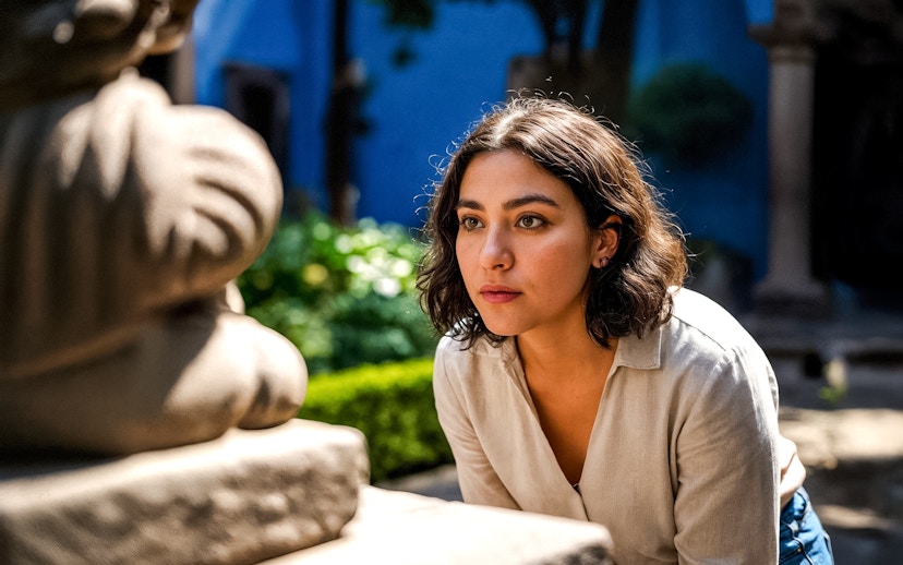 Tourist observing sculpture in Frida Kahlo Museum courtyard, Mexico City.