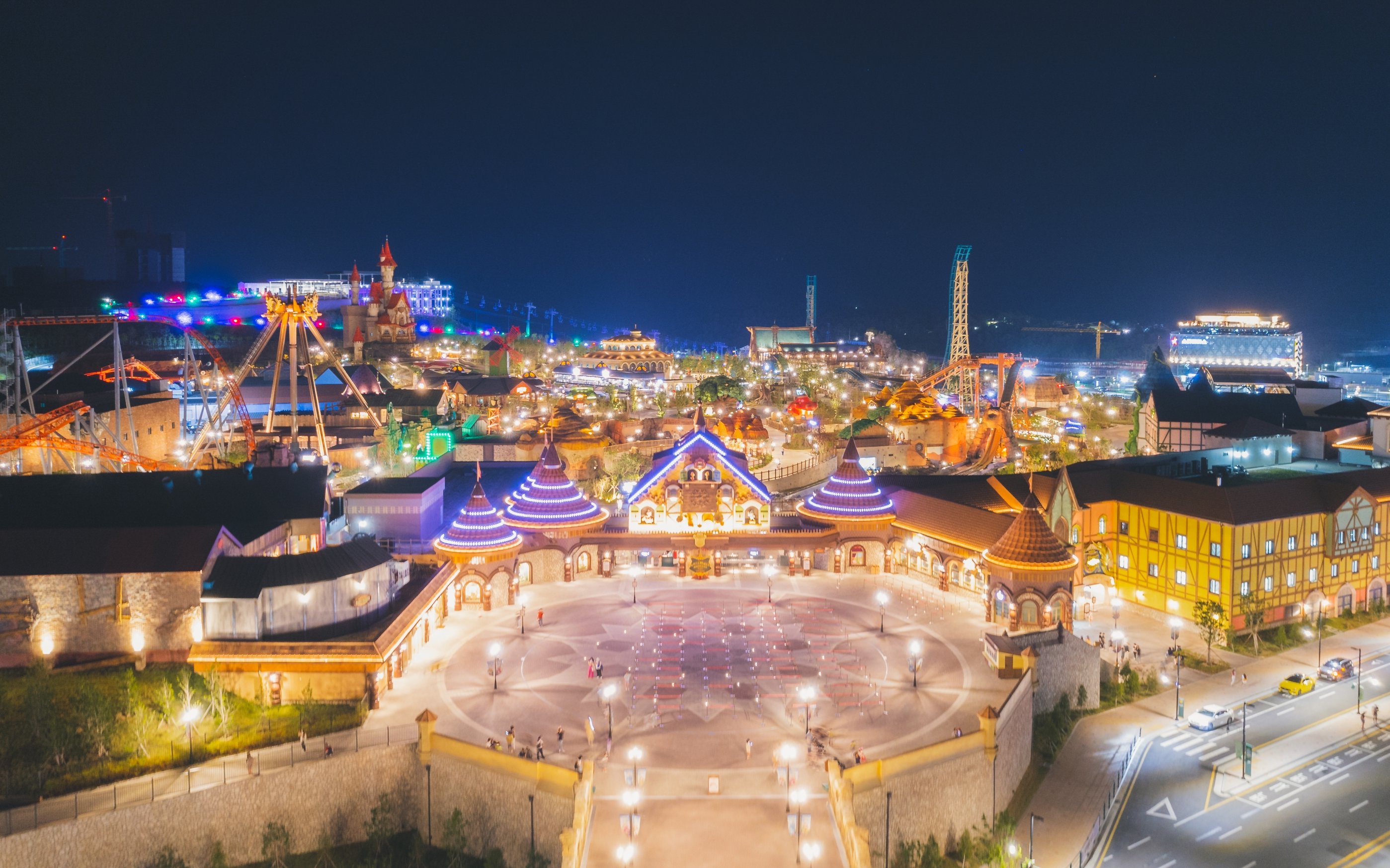 Nighttime aerial view of Lotte World Adventure Busan, featuring illuminated rides and attractions.