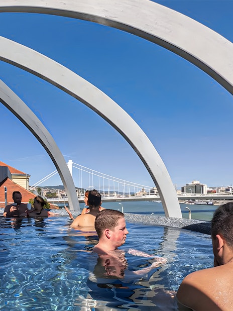 Visitors relaxing in the rooftop pool at Rudas Thermal Spa, Budapest, with city views.