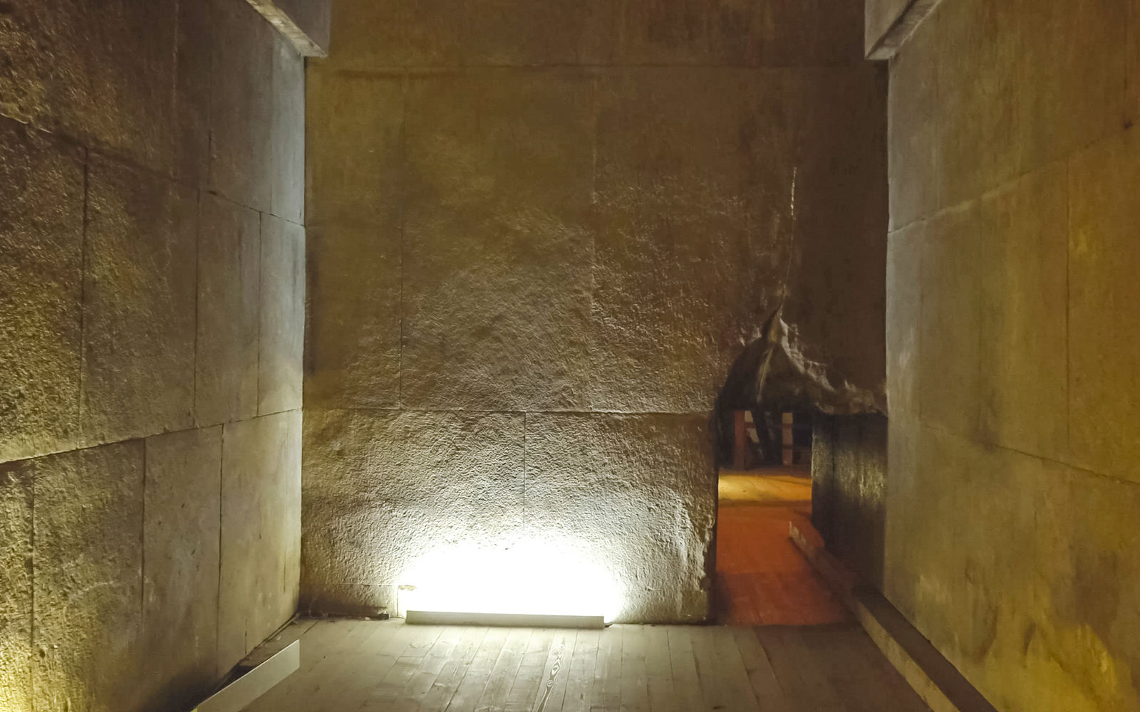 Interior passageway of the Pyramid of Menkaure, Giza, with stone walls and dim lighting.