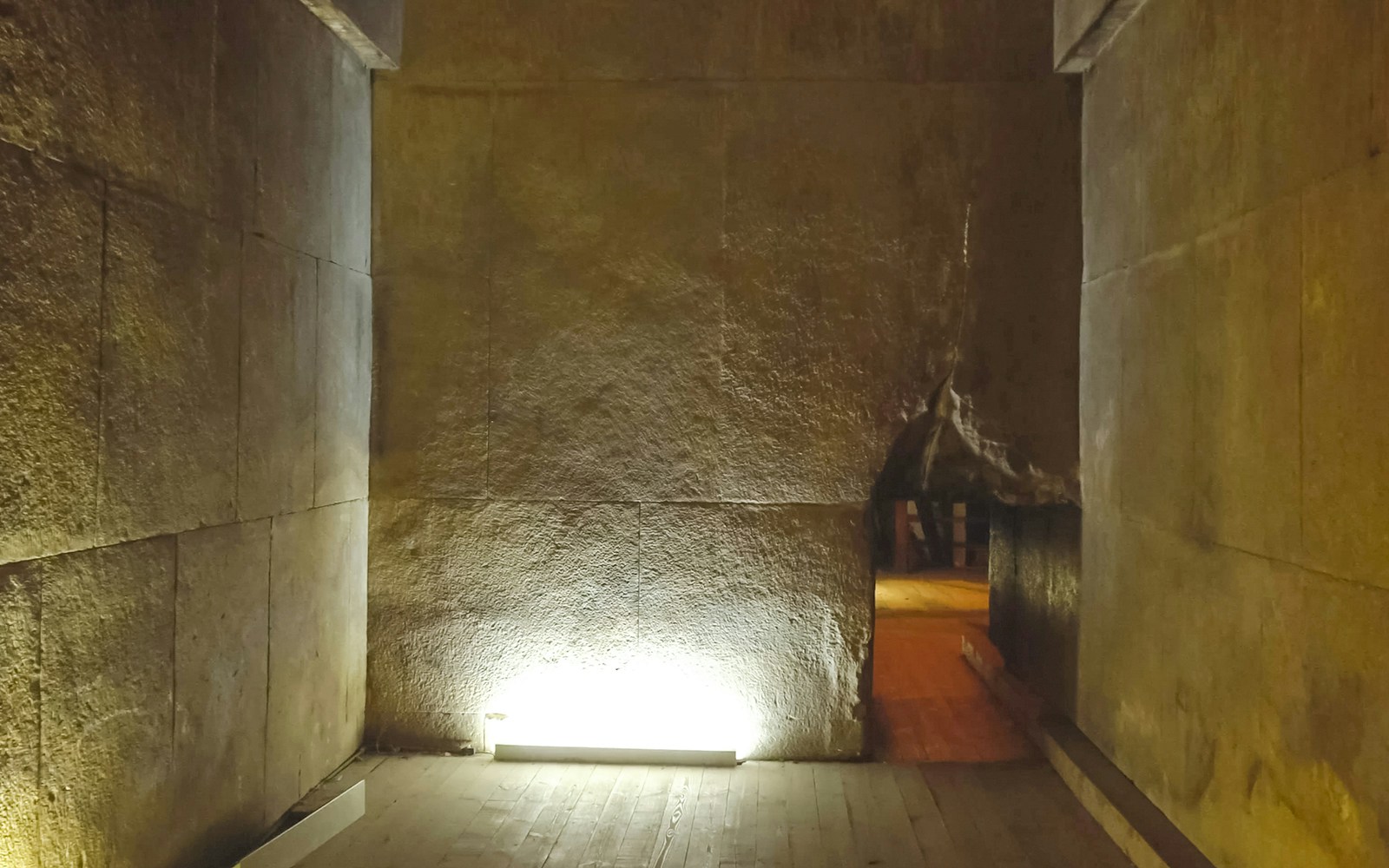Interior passageway of the Pyramid of Menkaure, Giza, with stone walls and dim lighting.