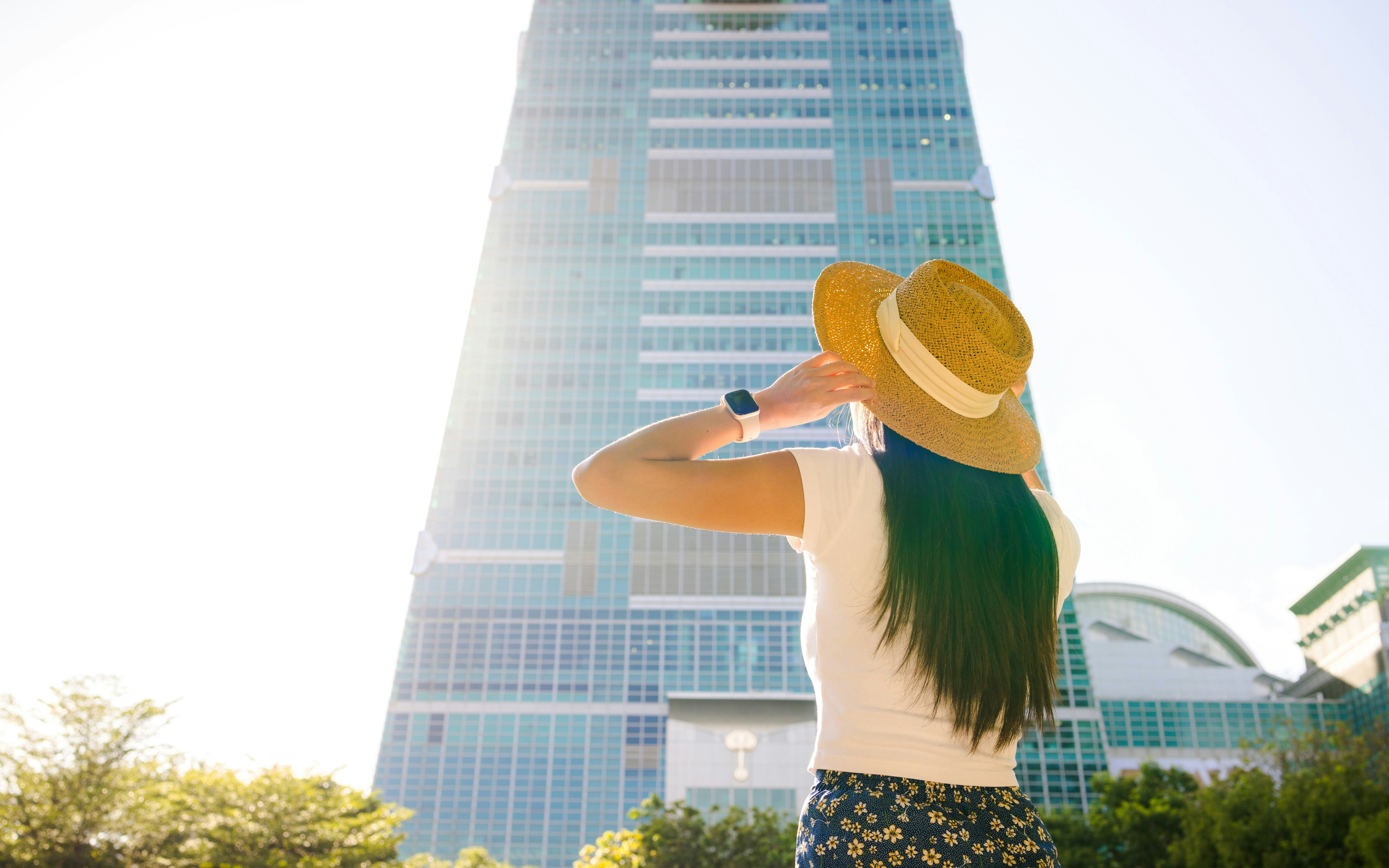 Tourist woman in hat looking up at Taipei 101 skyscraper in Taipei city.