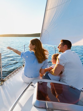 Family on cruise deck watching sunset over open water.