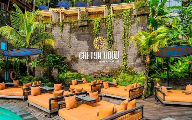 Poolside lounge area at Cretya Spa, Alas Harum Bali, with sunbeds and tropical plants.