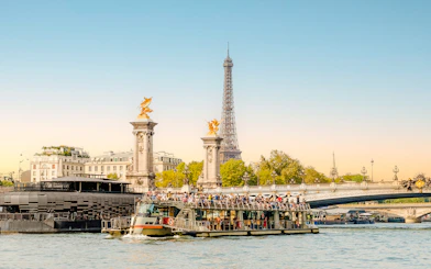 Cruise boat on Seine River with Eiffel Tower and Pont Alexandre III in Paris, France.