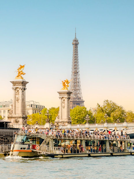 Cruise boat on Seine River with Eiffel Tower and Pont Alexandre III in Paris, France.