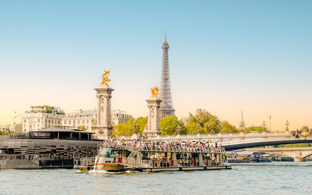 Cruise boat on Seine River with Eiffel Tower and Pont Alexandre III in Paris, France.