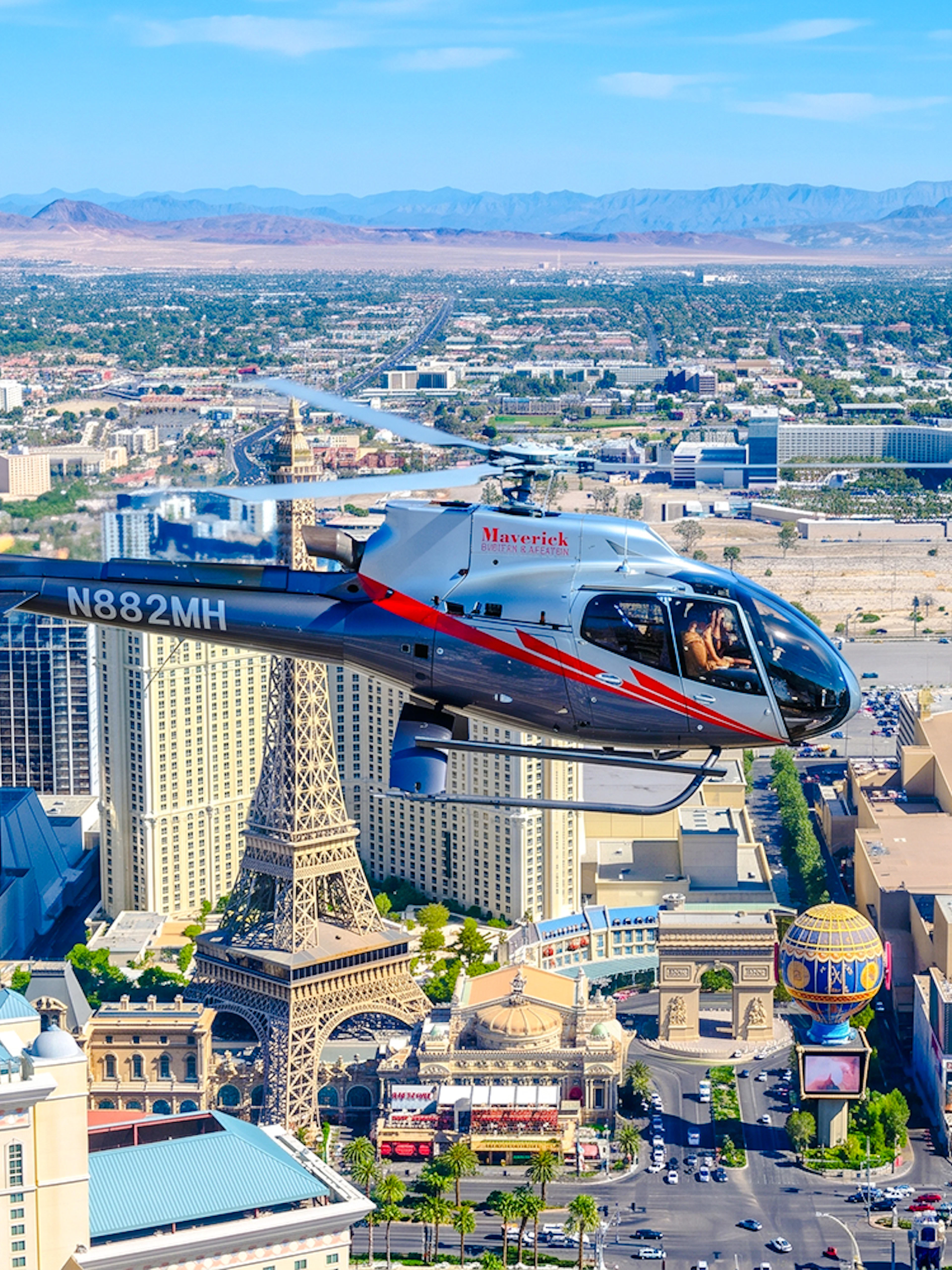 Helicopter flying over Las Vegas Strip with view of Paris Las Vegas and surrounding hotels.
