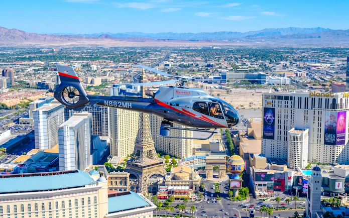 Helicopter flying over Las Vegas Strip with view of Paris Las Vegas and surrounding hotels.