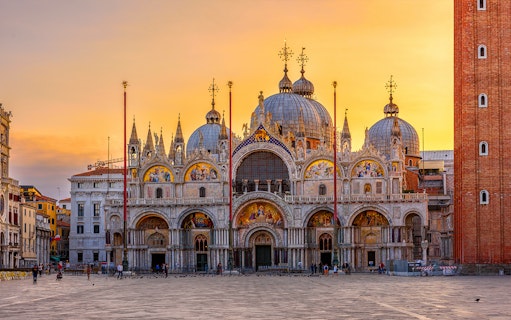 St. Mark's Basilica at sunset in Venice, Italy, with intricate mosaics and domes.