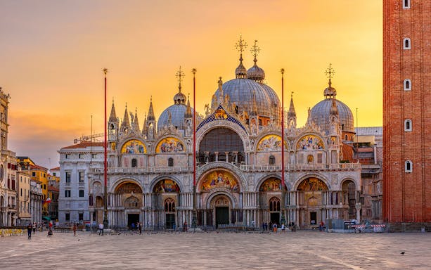 St. Mark's Basilica at sunset in Venice, Italy, with intricate mosaics and domes.
