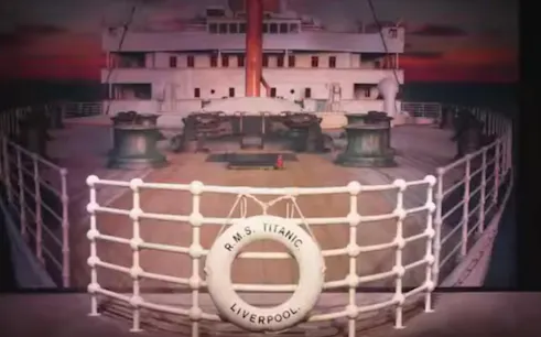 Titanic ship deck with lifebuoy labeled "R.M.S. Titanic Liverpool" at sunset, Houston exhibit.