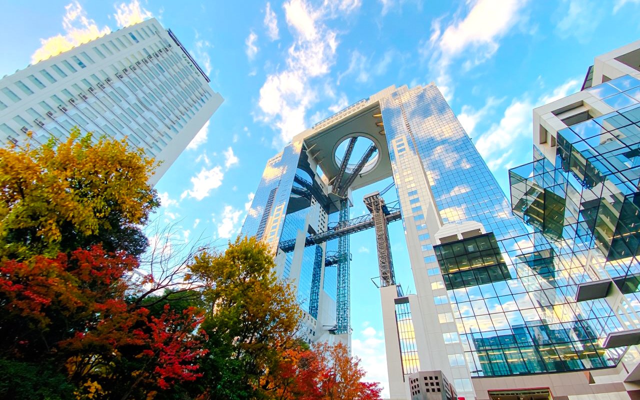 Umeda Sky Building in Osaka with autumn trees and blue sky.