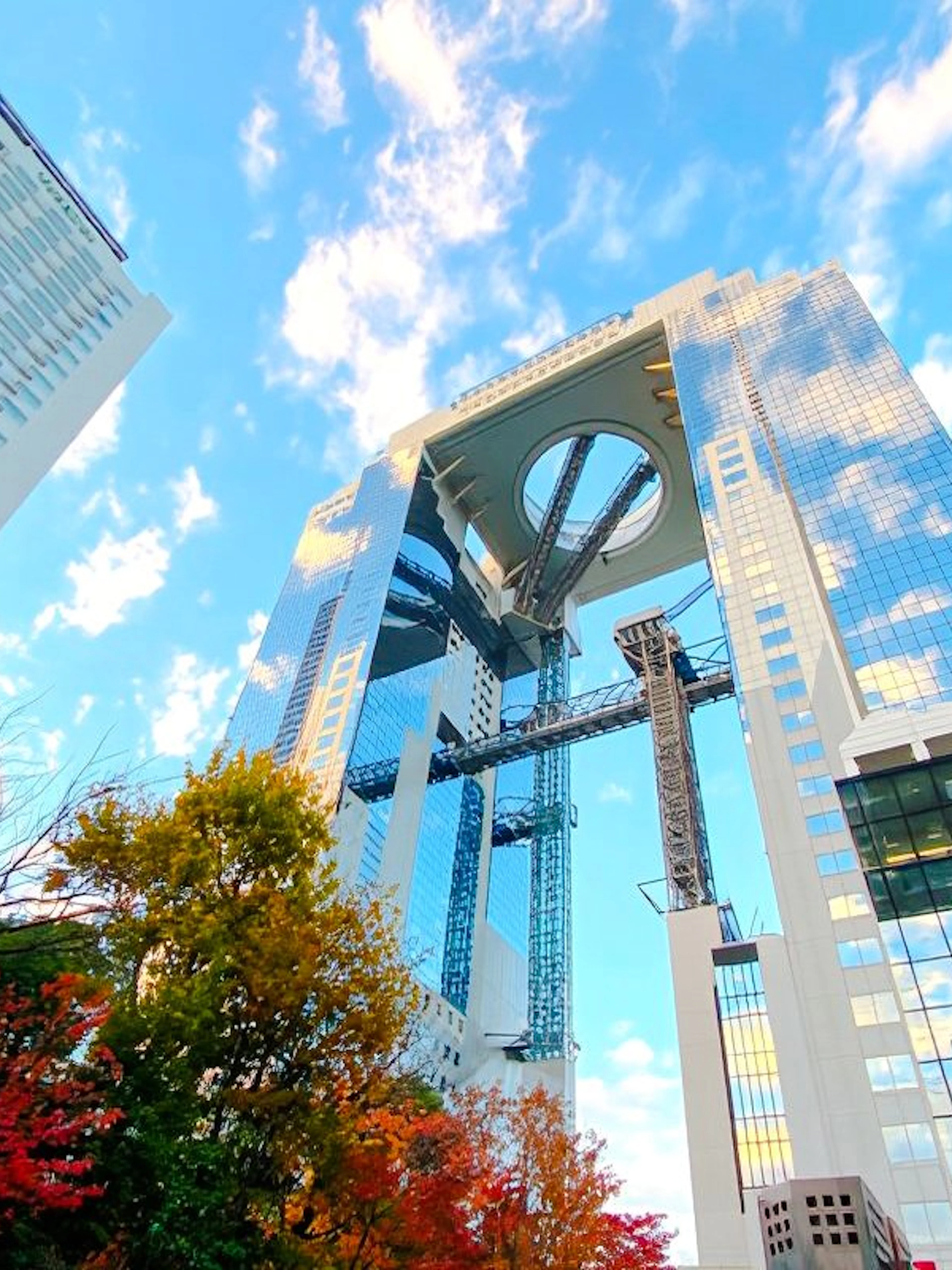 Umeda Sky Building in Osaka with autumn trees and blue sky.