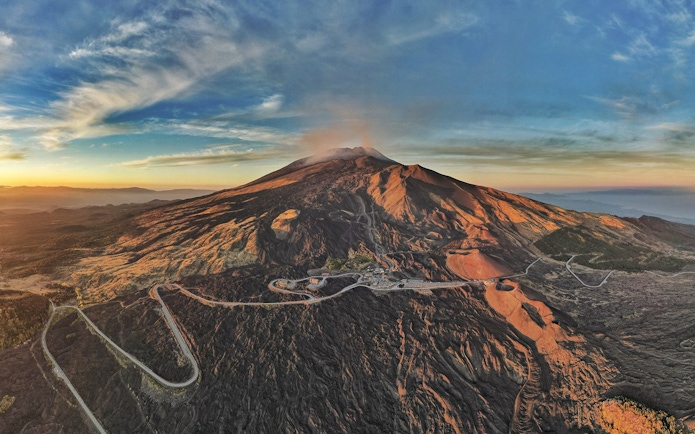 Mount Etna aerial view at sunset with volcanic craters and rugged landscape in Catania, Italy.