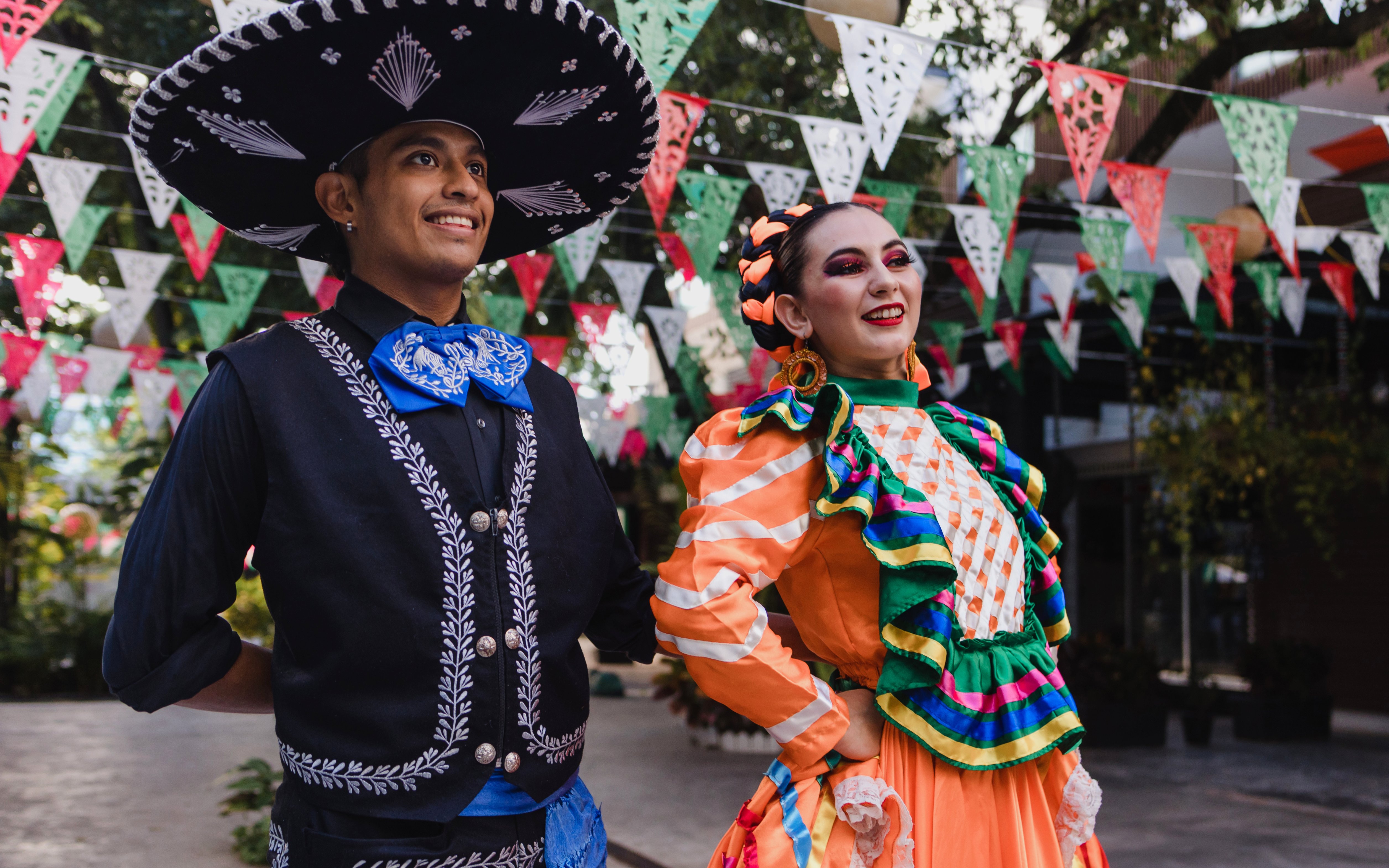 Traditional dancers in colorful attire celebrating Cinco de Mayo with festive banners.