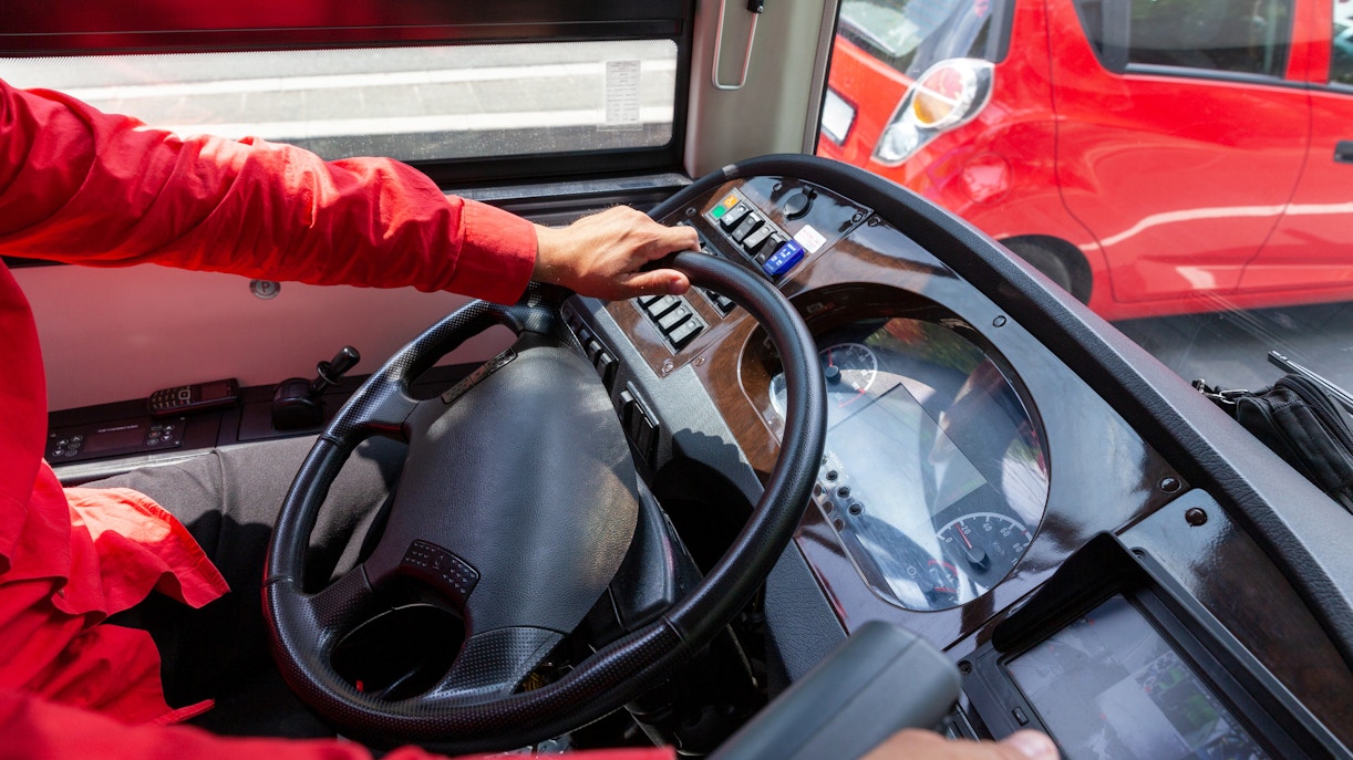Bus driver steering a vehicle, showcasing professional driving skills.