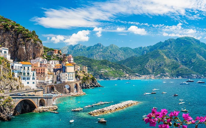 Coastal view of Sorrento with colorful buildings and boats on the blue sea.