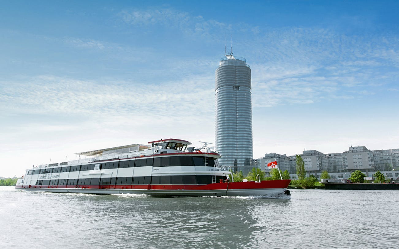 Cruise ship on the Danube River with Vienna's skyline in the background.