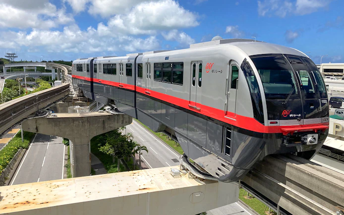 Okinawa Monorail train traveling on elevated tracks under a blue sky.