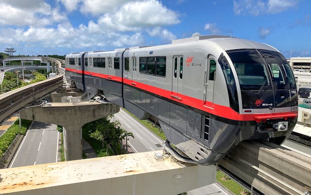 Okinawa Monorail train traveling on elevated tracks under a blue sky.