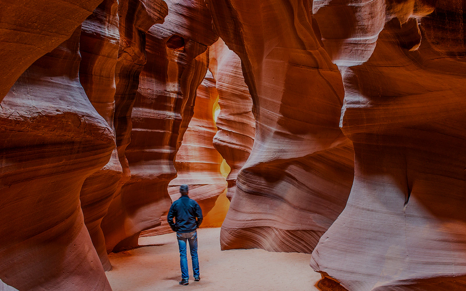 Person exploring narrow sandstone walls in Upper Antelope Canyon, Arizona.