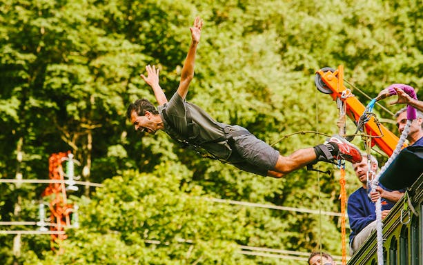 Man bungee jumping with AJ Hackett in a forest setting.