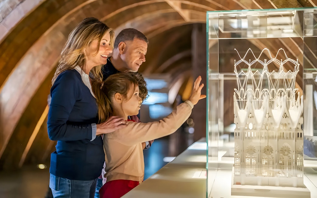 Family observing Casa Mila miniature in Barcelona exhibit.