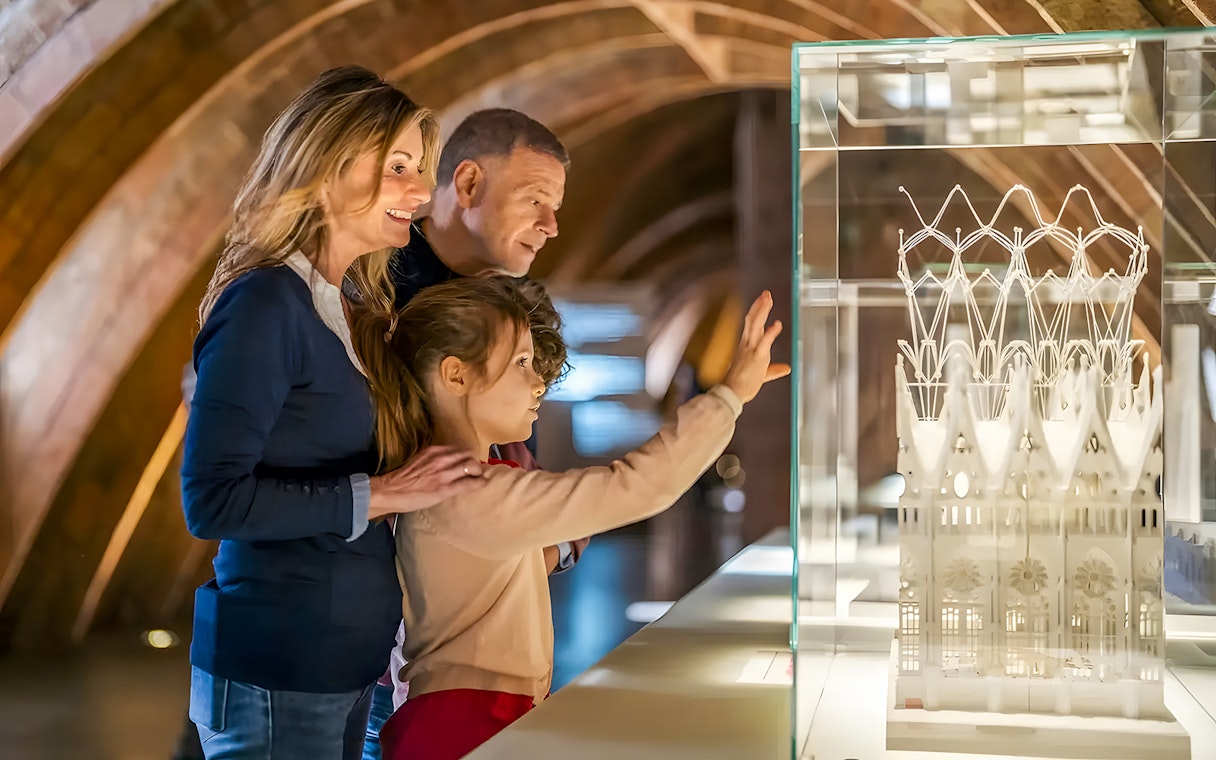 Family observing Casa Mila miniature in Barcelona exhibit.