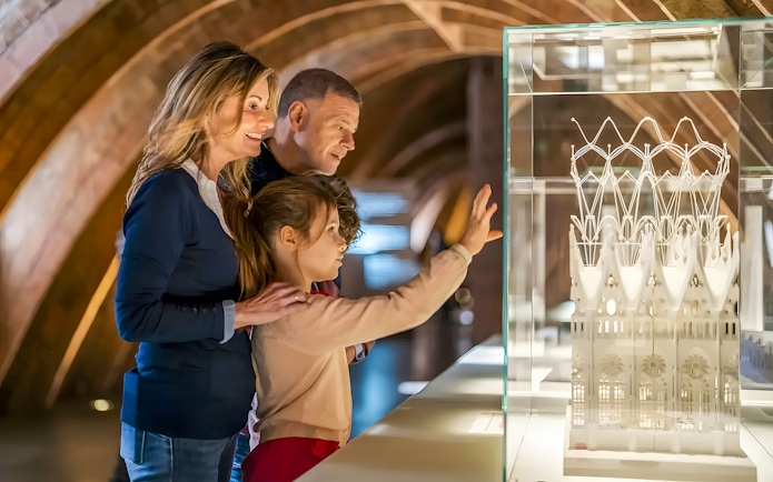 Family observing Casa Mila miniature in Barcelona exhibit.