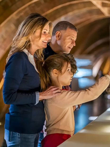 Family observing Casa Mila miniature in Barcelona exhibit.