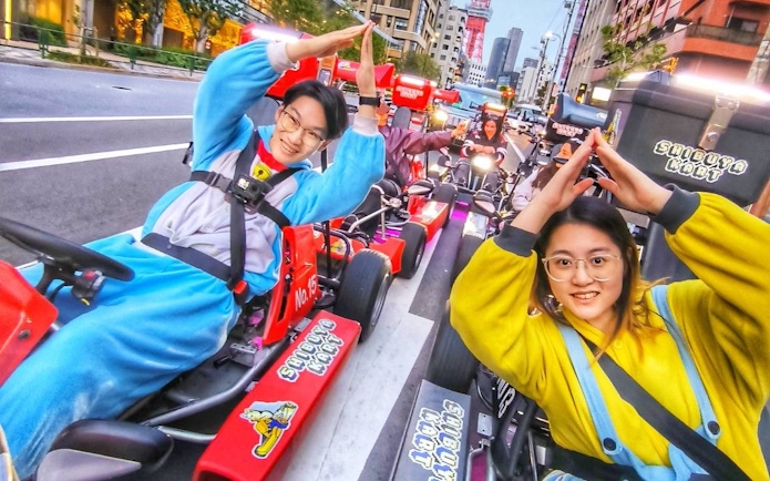 Go-kart riders in costumes on Shibuya streets during guided tour in Tokyo.
