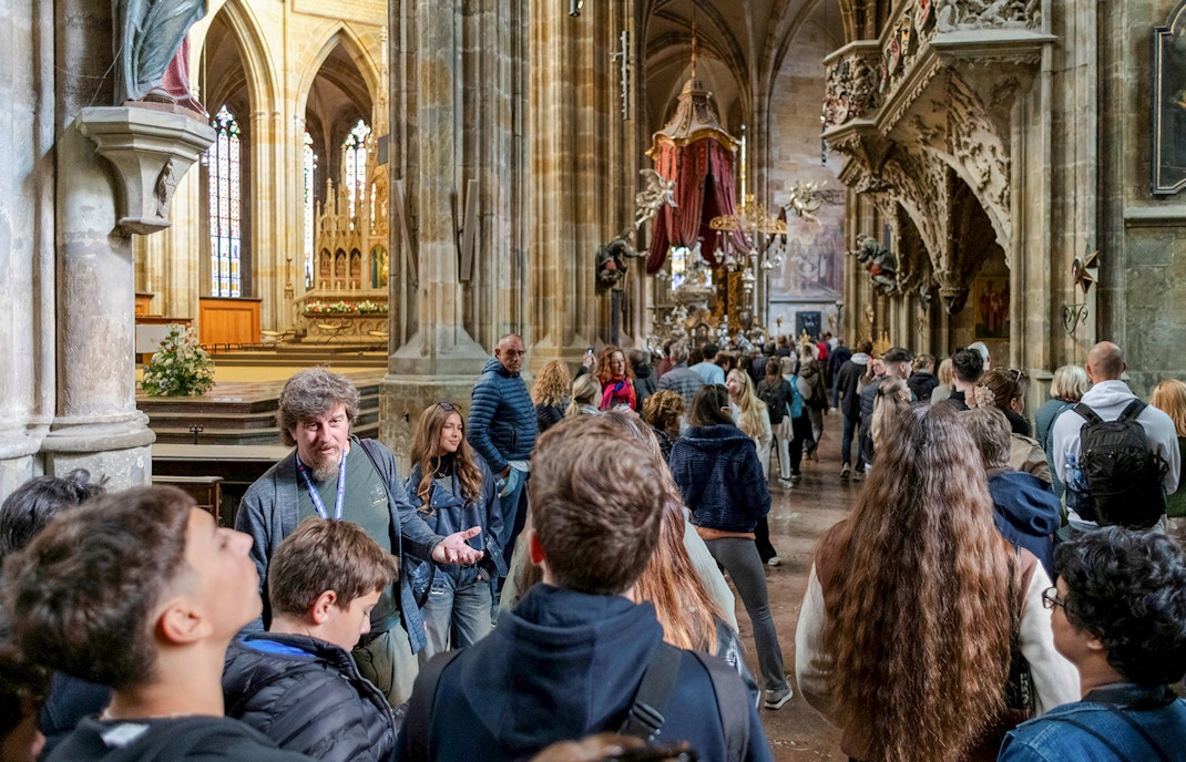 Prague Castle interior with tourists on a guided tour exploring historic architecture.