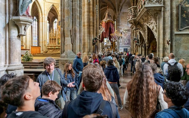 Tour group exploring Prague Castle interior with guide.