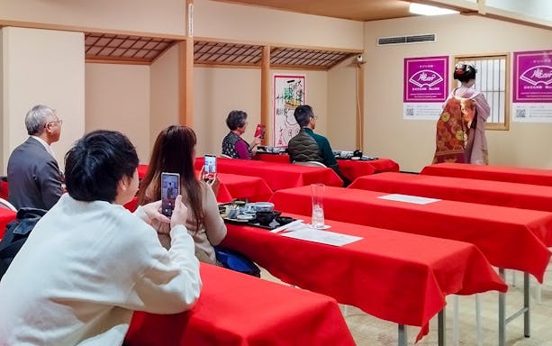 Guests watching a Maiko dance performance during a tea ceremony in a traditional Japanese setting.