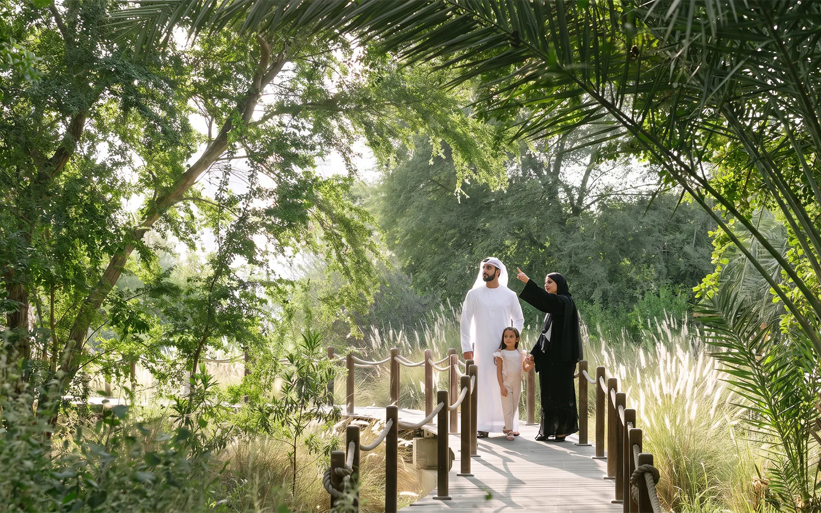 Family exploring lush greenery on Al Noor Island boardwalk.