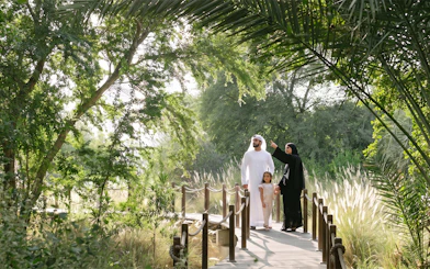 Family exploring lush greenery on Al Noor Island boardwalk.